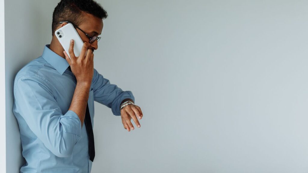 Dire non sans perdre tes relations : le guide pour protéger ton temps et tes objectifs Homme d'affaires au téléphone qui vérifie l'heure sur sa montre