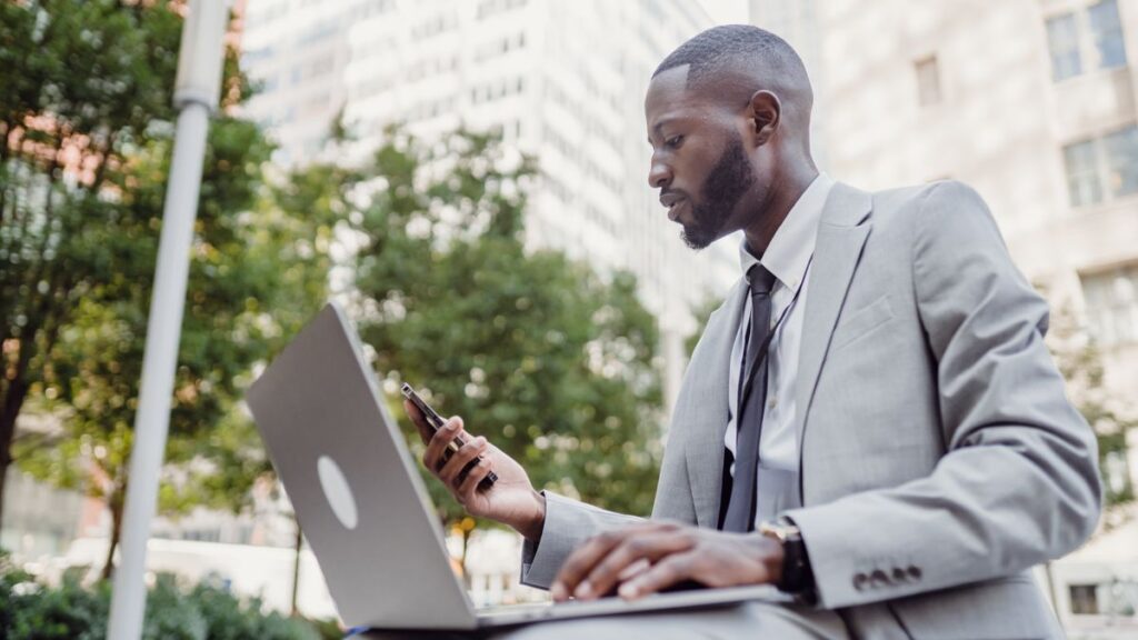 Arrête d’attendre ta chance en Afrique : 10 opportunités que tu peux saisir avec ton téléphone Homme d'affaires africain qui utilise son téléphone et son ordinateur