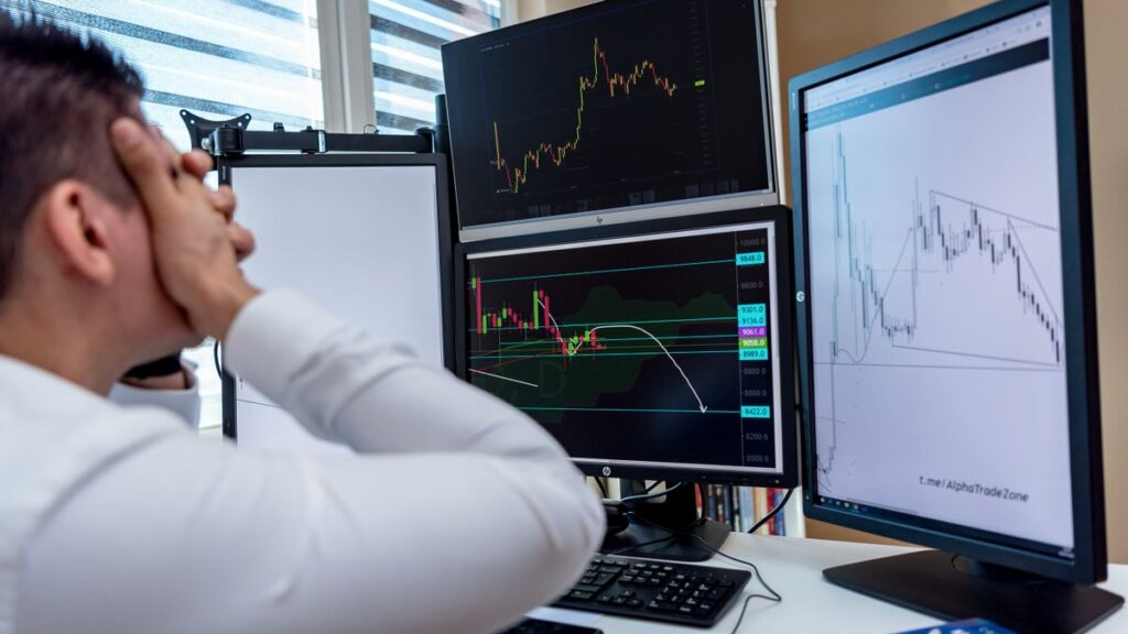 Peur, cupidité, FOMO : les 3 pièges des investisseurs débutants (et comment les éviter) Trader devant plusieurs écrans de marchés