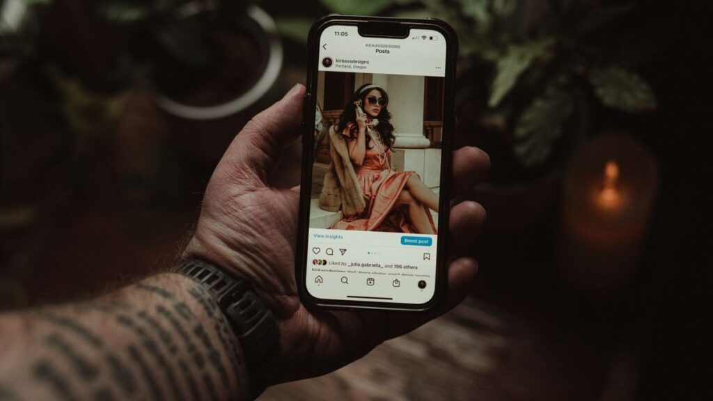 Le vrai prix de la réussite jeune : ce que personne ne te montre sur Instagram Main tenant un smartphone qui affiche un profil Instagram